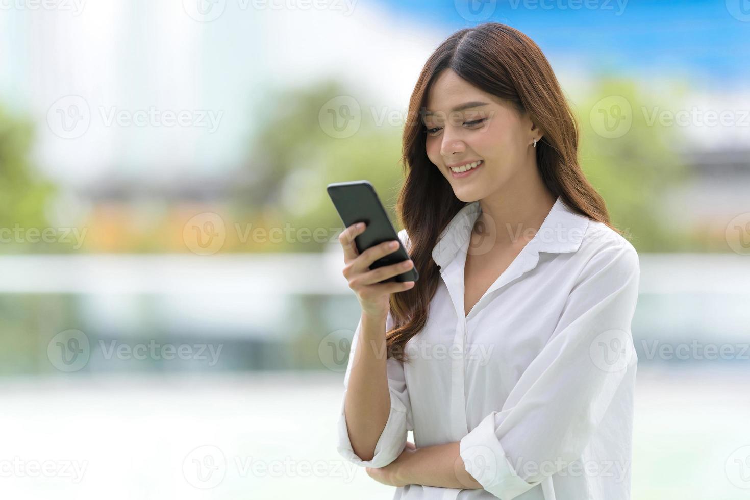 buitenshuis portret van gelukkige jonge vrouw met behulp van een telefoon foto