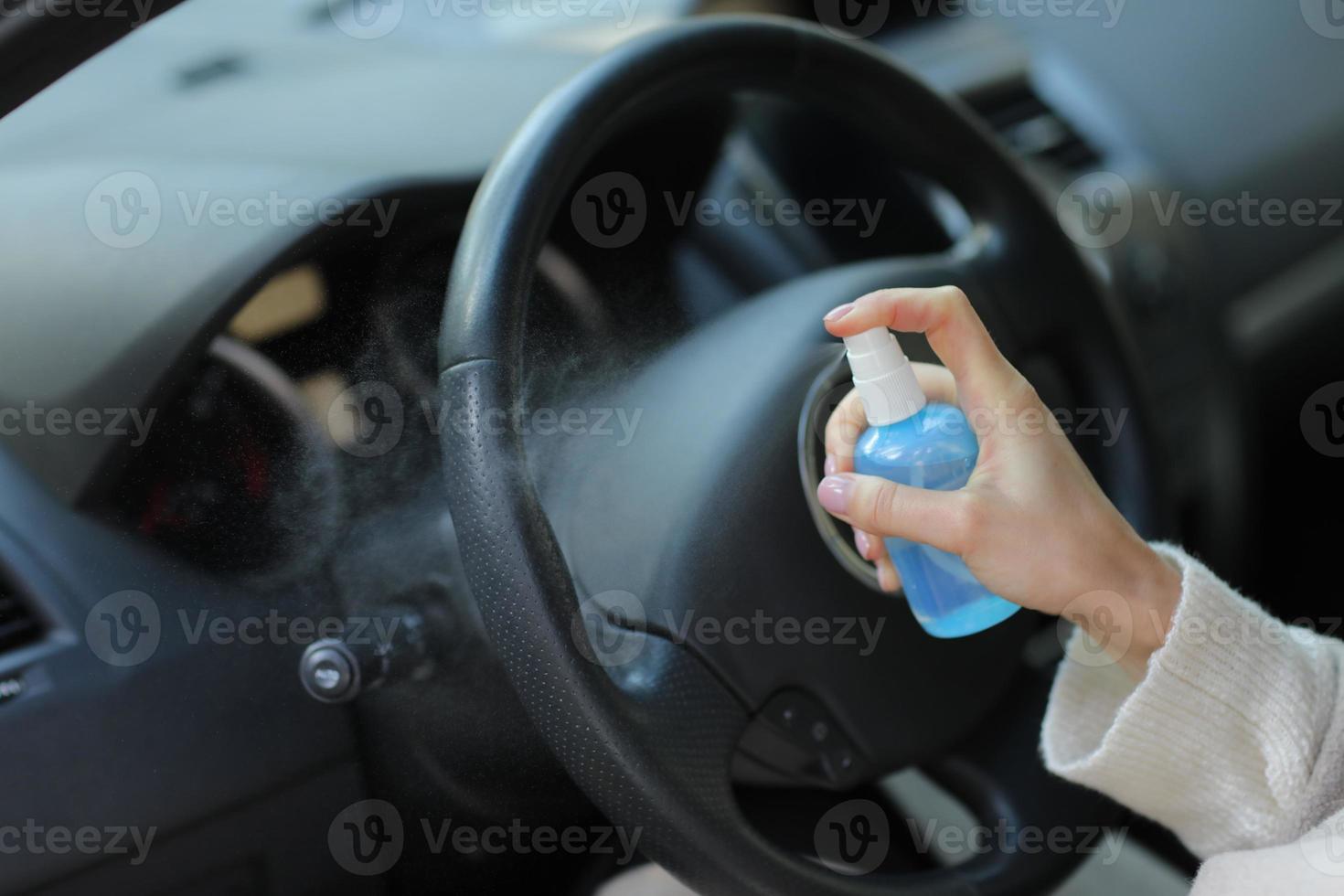 hand van vrouw spuit alcohol, desinfecterende spray in auto, veiligheid, voorkom infectie van covid 19-virus, coronavirus, besmetting van ziektekiemen of bacteriën.alcoholdesinfecterend middel, hygiëneconcept. foto