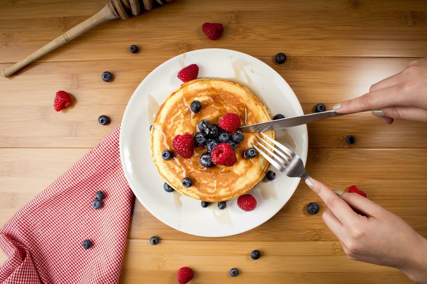 aan het eten bosbes pannekoeken - handen van jong vrouw foto