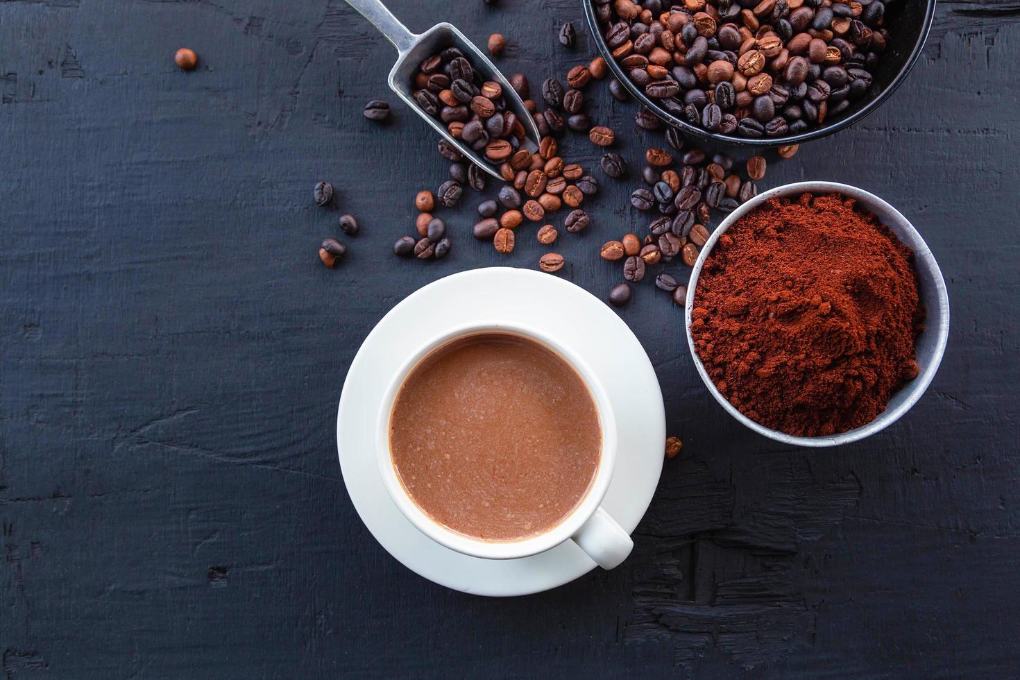 gebrande koffiebonen met koffiepoeder en koffiekopjes. foto