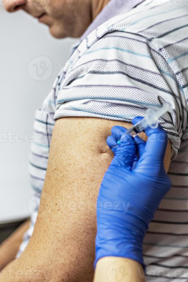 een arts vaccineert een man tegen het coronavirus in een kliniek. detailopname. het concept van vaccinatie, immunisatie, preventie tegen covid-19. foto