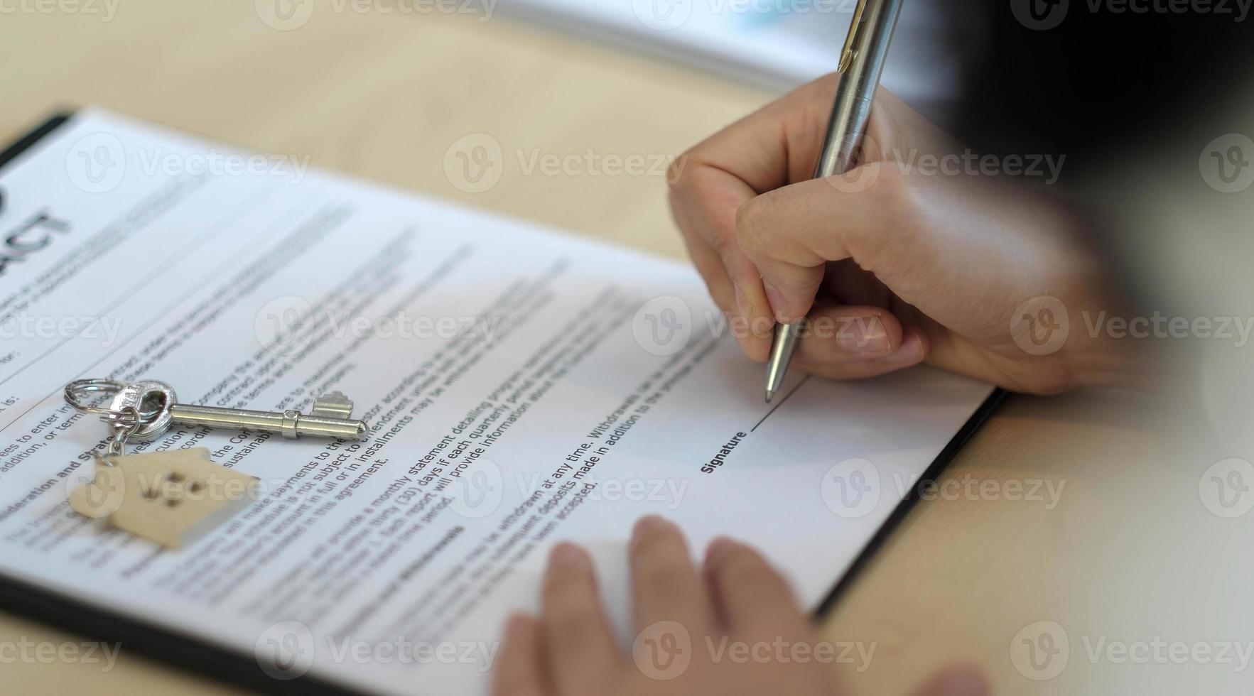 close-up weergave handen van zakenman ondertekening leasing huis documenten en hebben een appartement sleutels op papierwerk. foto