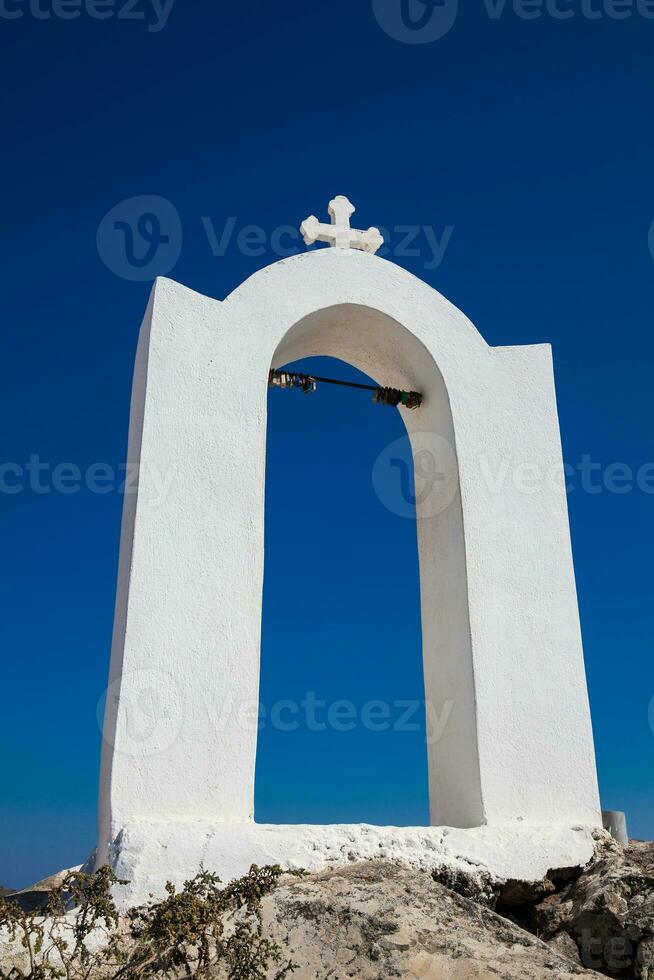 mooi klein klok toren Bij een kerk De volgende naar de wandelen pad tussen fira en oia in Santorini eiland foto