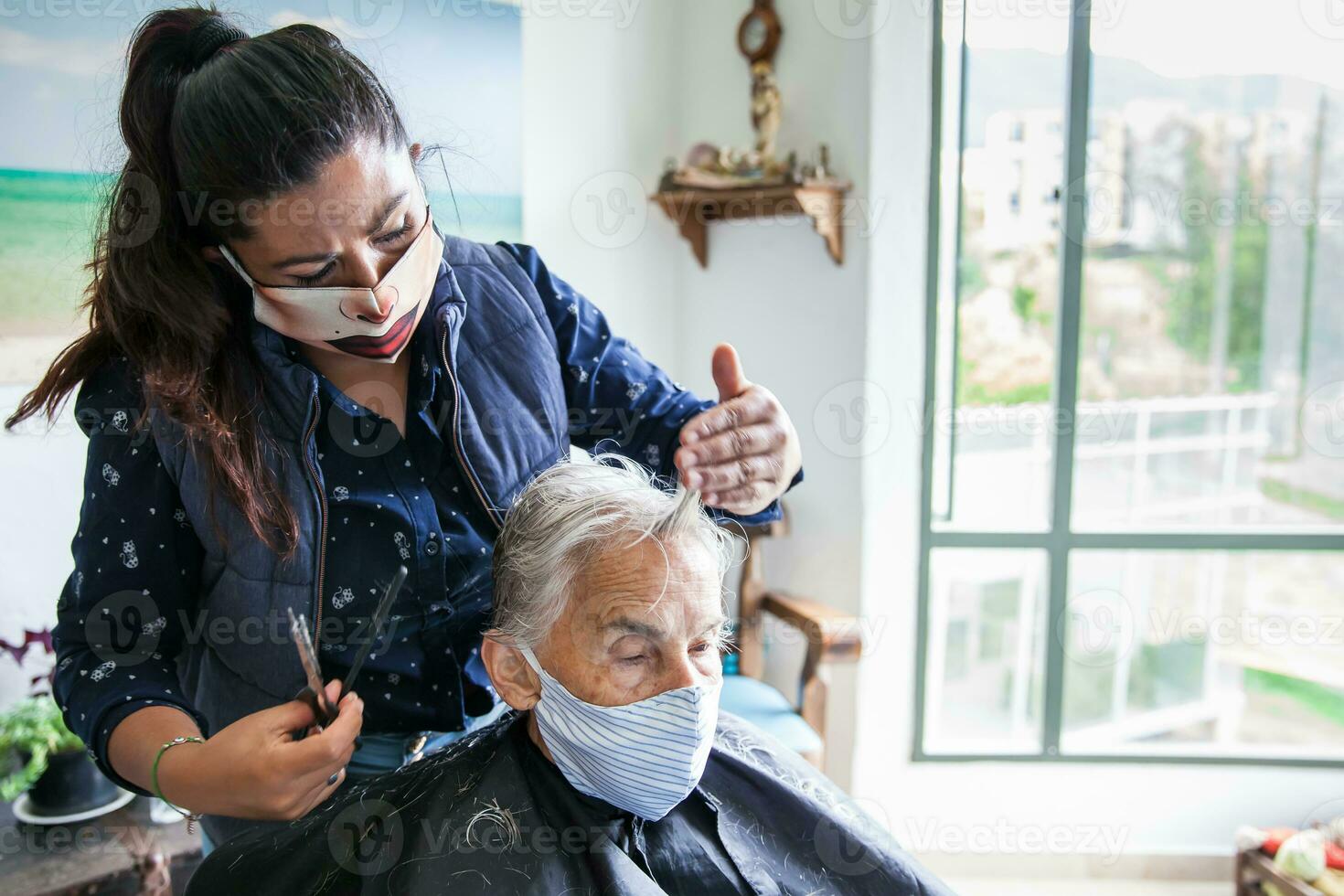 senior vrouw krijgen een kapsel Bij huis gedurende covid19 pandemisch vervelend gezicht masker foto