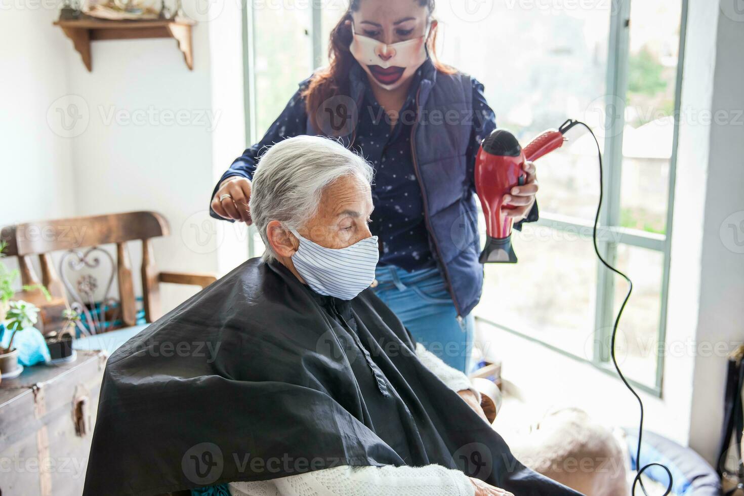 senior vrouw krijgen een kapsel Bij huis gedurende covid19 pandemisch vervelend gezicht masker foto