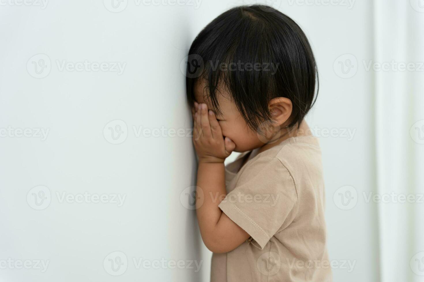 weinig Aziatisch kinderen kind meisje aan het bedekken zijn ogen met handen, spelen verbergen en zoeken staand De volgende een muur huis, aanbiddelijk kind hebben pret in de huis. gelukkig familie hebben pret met kinderen, werkzaamheid foto