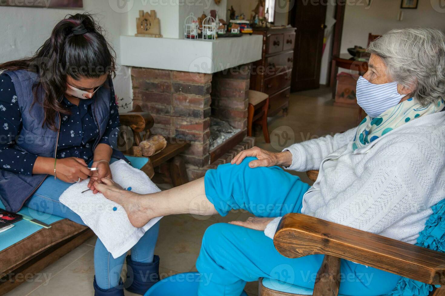 pedicure maken een pedicure naar een senior vrouw Bij huis gedurende covid 19 pandemisch vervelend gezicht masker foto