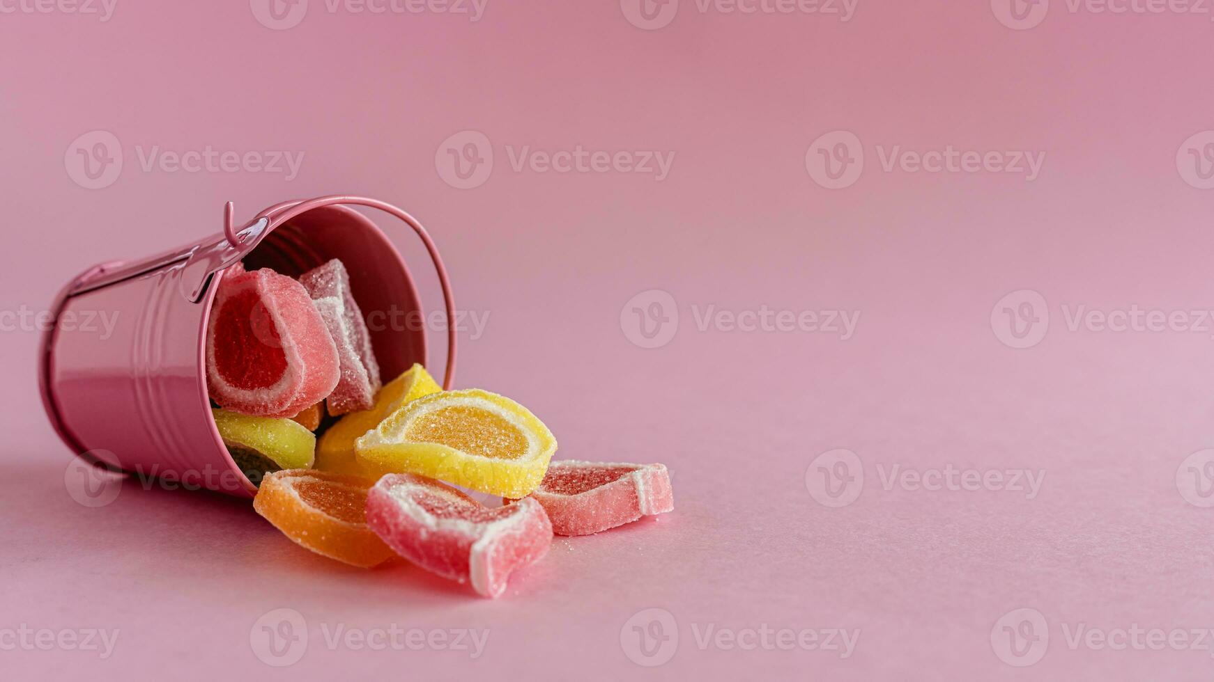 kleurrijk fruit gelei snoep in een roze emmer foto