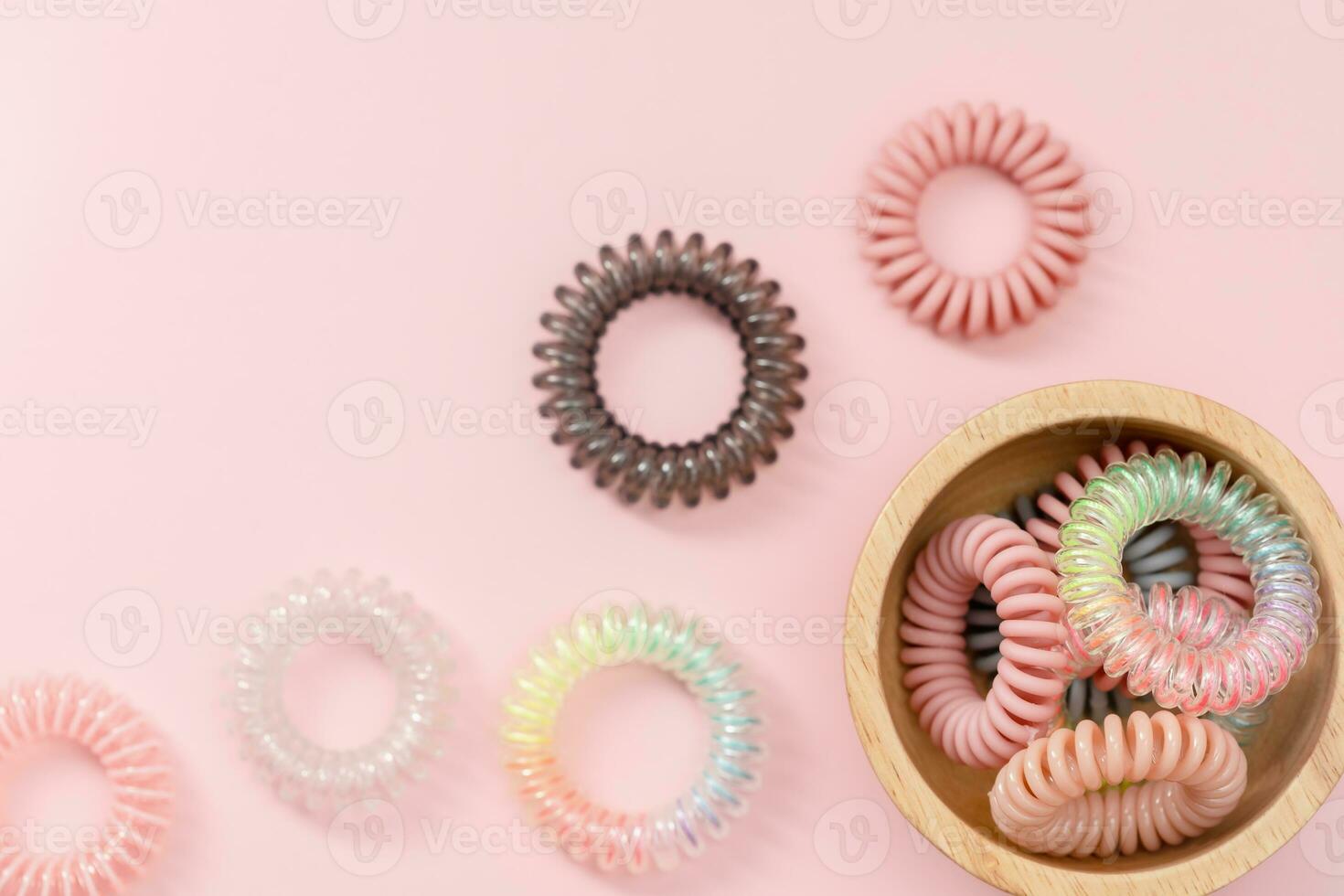 de houten kom van spiraal haar- rubber bands Aan roze achtergrond foto