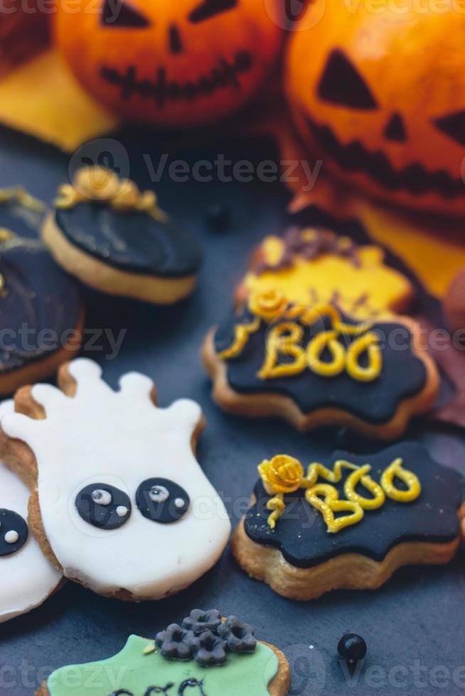 Halloween-peperkoekkoekjes op donkere achtergrond, met Halloween-minipompoenen en decoratie foto