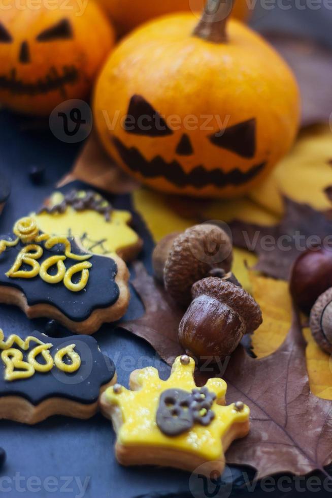 Halloween-peperkoekkoekjes op donkere achtergrond, met Halloween-minipompoenen en decoratie foto