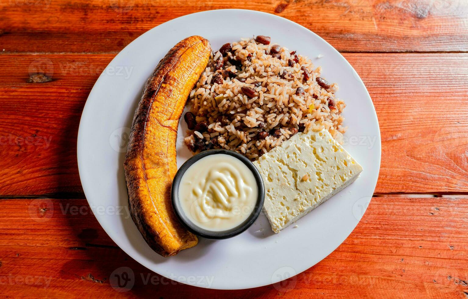 galopperen bord met kaas en maduro Aan houten tafel. Nicaraguaanse voedsel concept, traditioneel gallo pinto maaltijd met maduro en kaas geserveerd foto