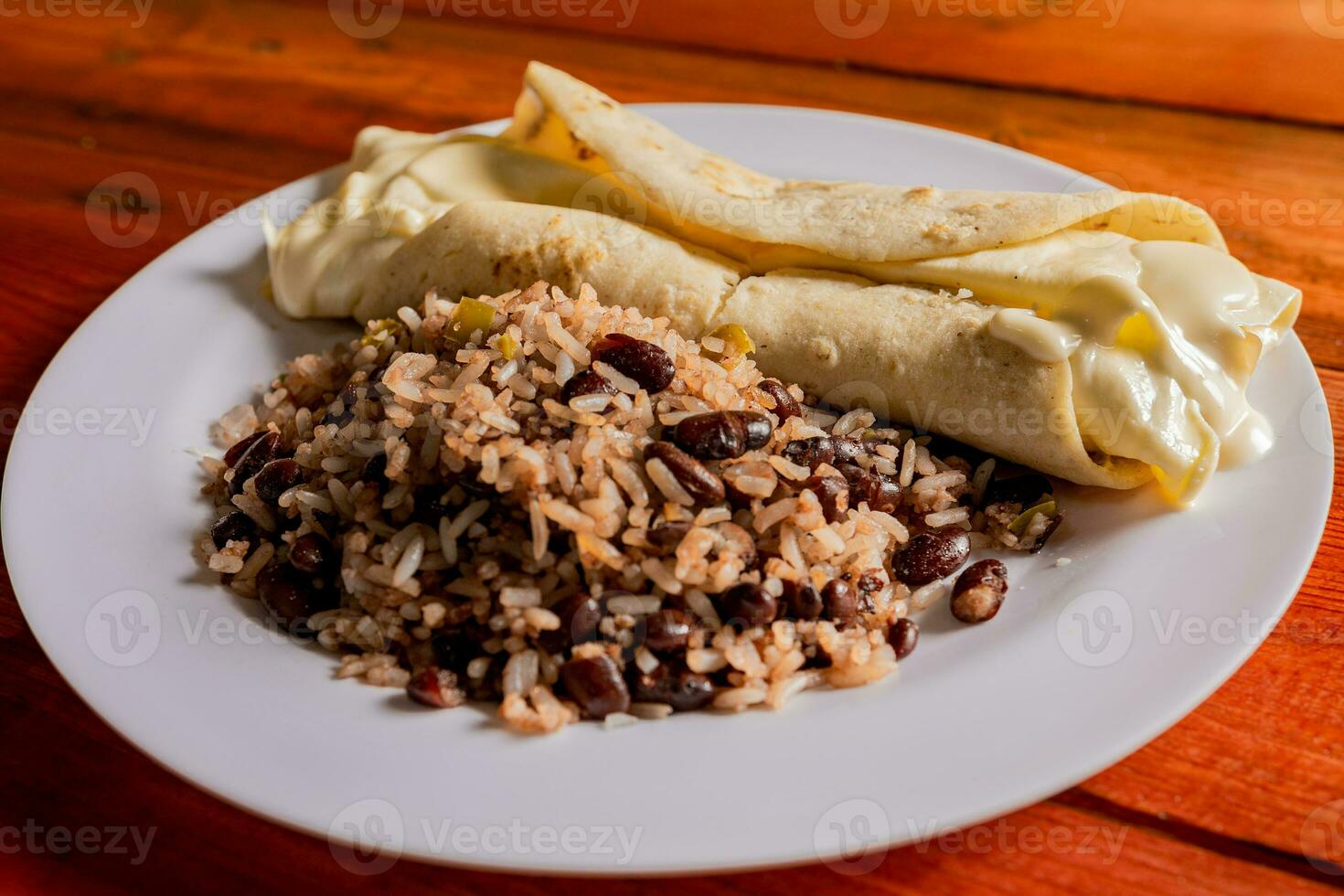 traditioneel gallo pinto met quesillo geserveerd Aan houten tafel. Nicaraguaanse galopperen met quesillo Aan de tafel. typisch Nicaraguaanse voedingsmiddelen foto