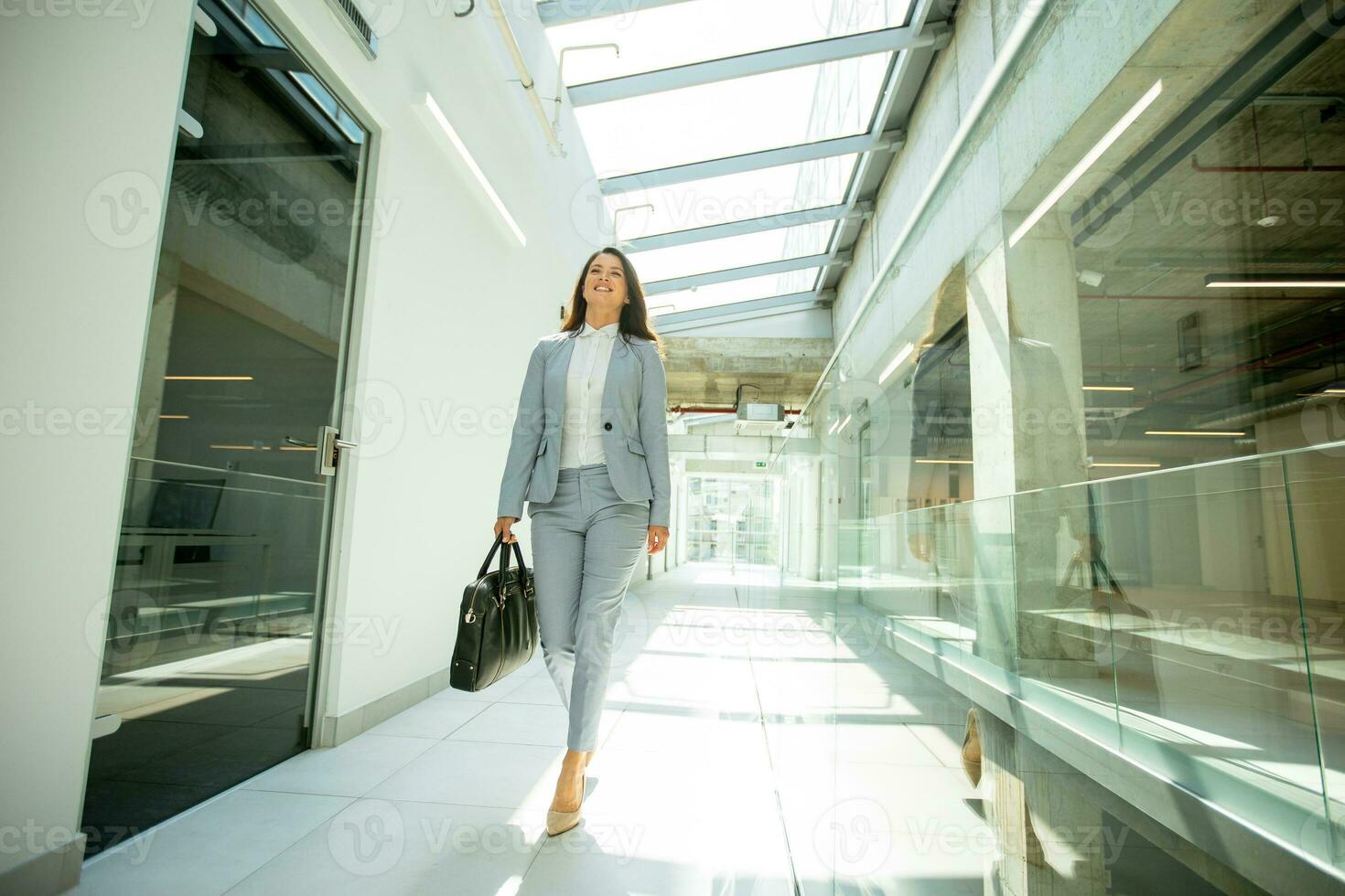 mooi jong bedrijf vrouw wandelen met aktentas in de kantoor gang foto