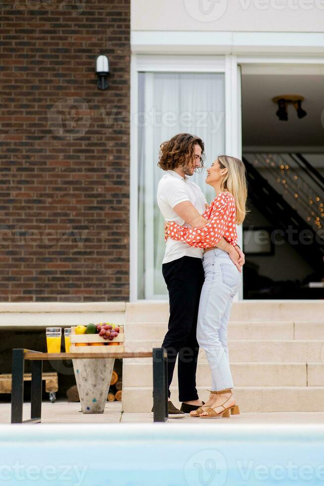 jong paar ontspannende door de zwemmen zwembad in de huis achtertuin foto