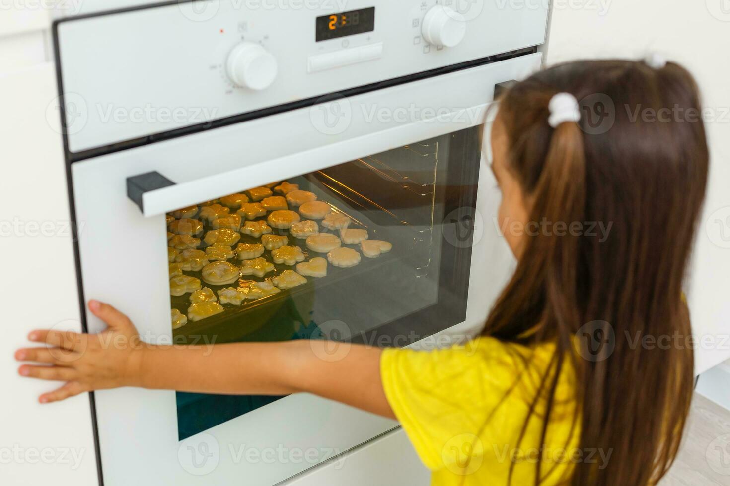 weinig meisje maken koekjes Bij de komst tijd. foto