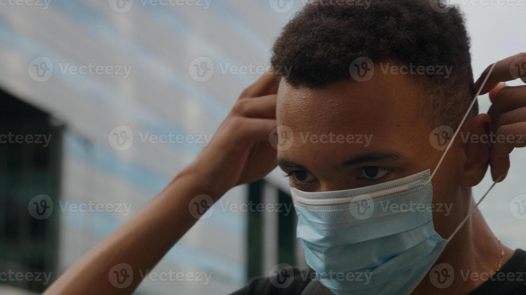 portret van een jonge man die een beschermend gezichtsmasker opzet foto