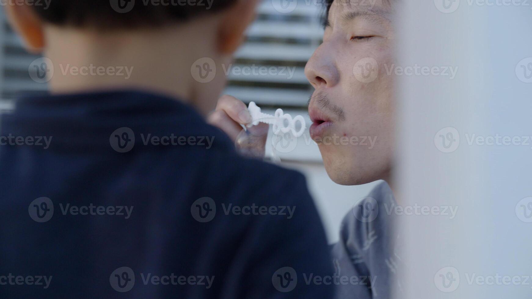 portret van vader en zoon spelen met zeepbellen foto