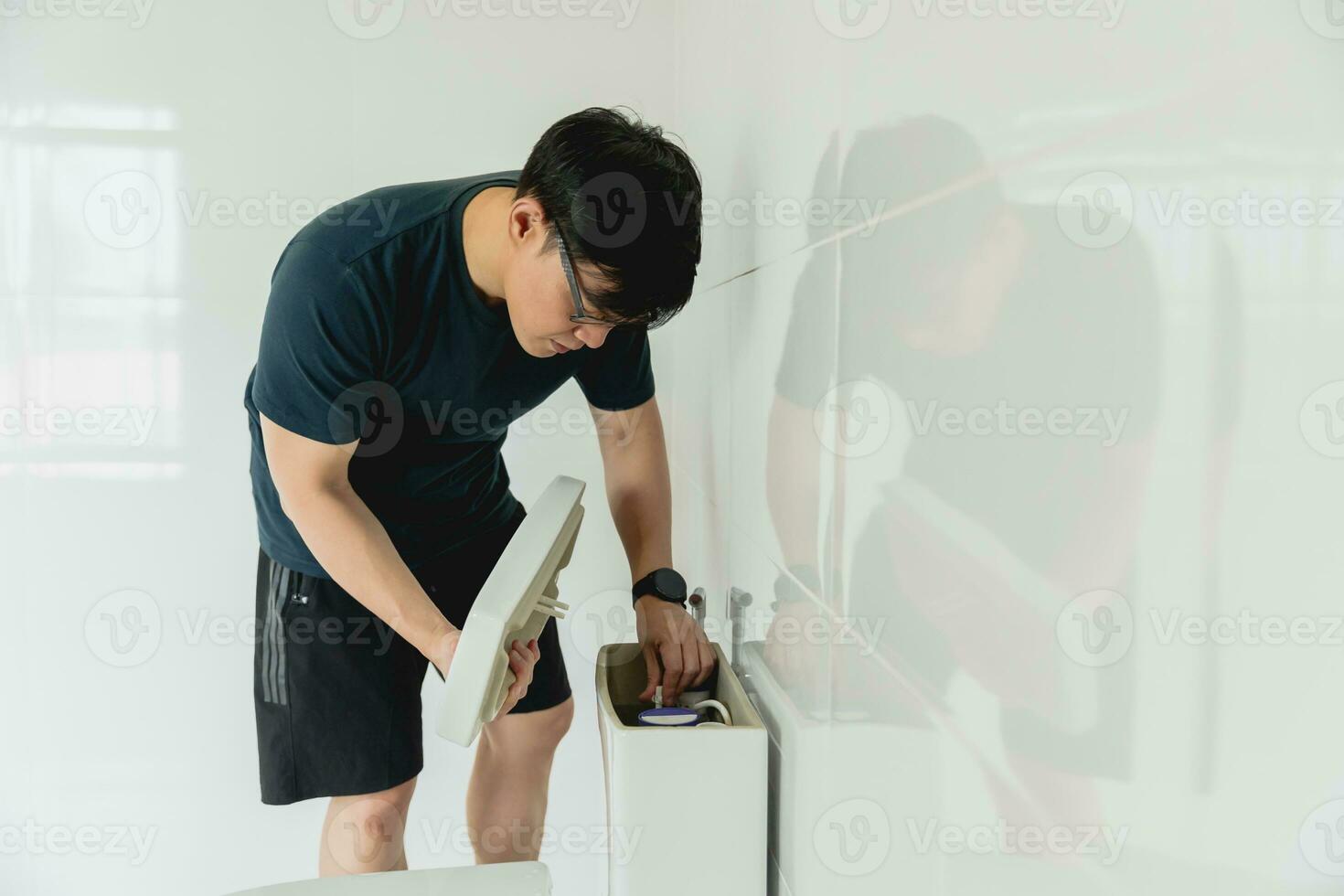 Mens aan het doen karwei huis werk worden klusjesman repareren de toilet tank in de badkamer foto