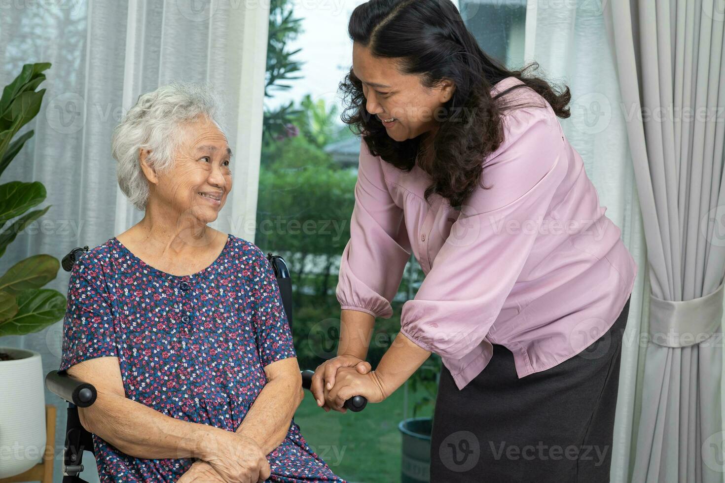 verzorger helpen Aziatisch senior vrouw Aan rolstoel met liefde Bij huis. foto