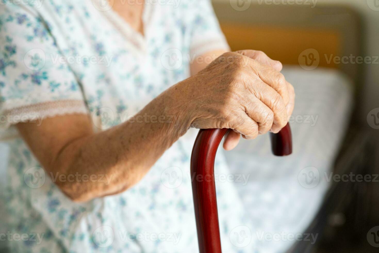 Aziatisch ouderen onbekwaamheid vrouw Holding wandelen stok, hout riet, ronde handvat, wandelen steun voor helpen naar wandelen. foto