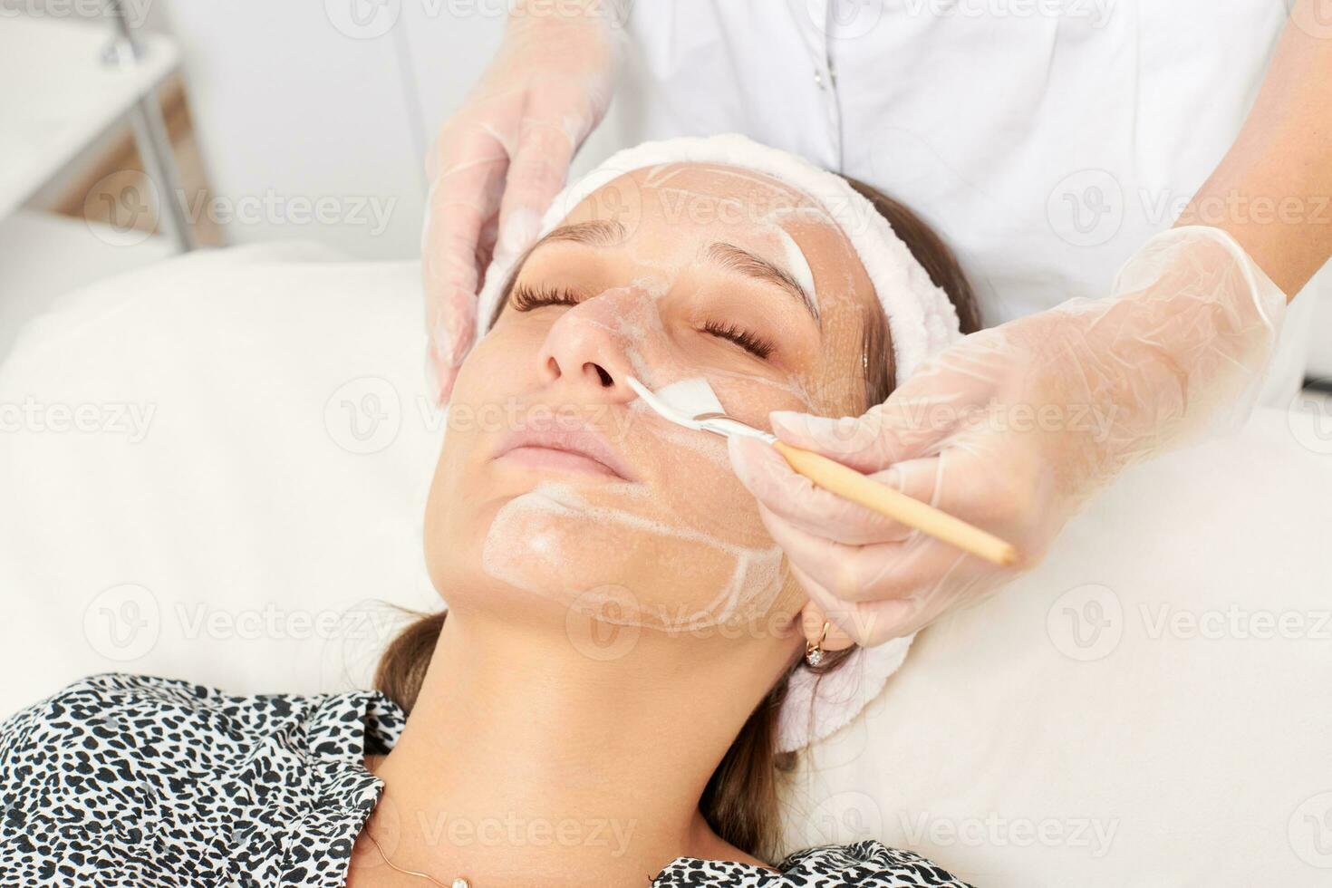 schoonheidsspecialist toepassen kunstmatig room masker Aan vrouw gezicht voor verjonging, procedure in schoonheid salon foto