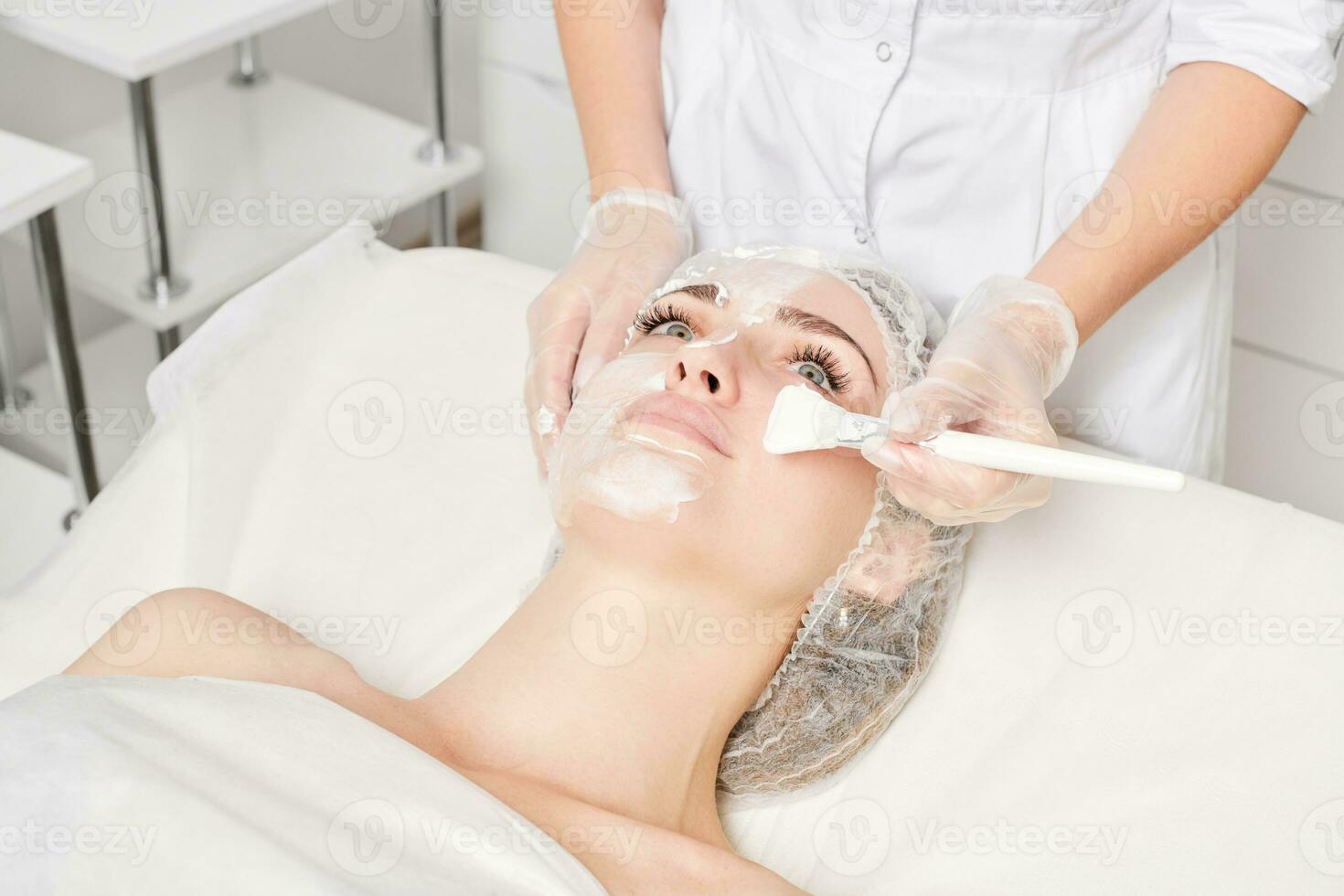 schoonheidsspecialist is van toepassing room masker Aan vrouw gezicht voor verjonging gezicht huid, procedure in schoonheid salon foto