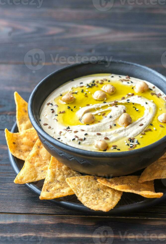 kom van hummus met tortilla chips foto