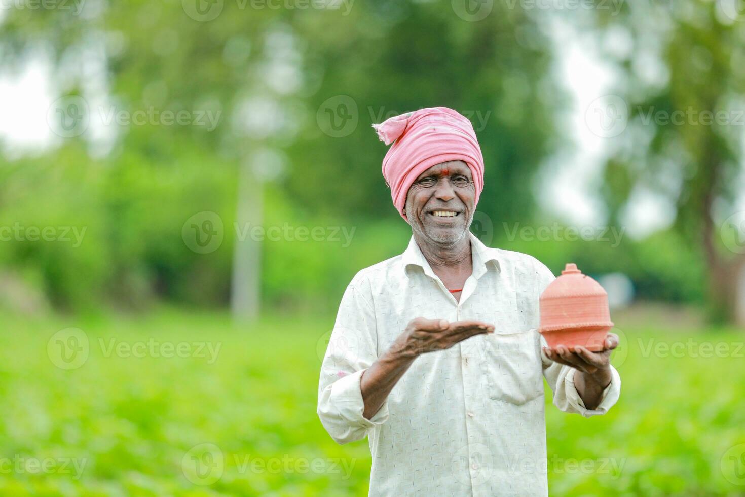 Indisch boer Holding gullak in hand, besparing concept, gelukkig arm boer foto