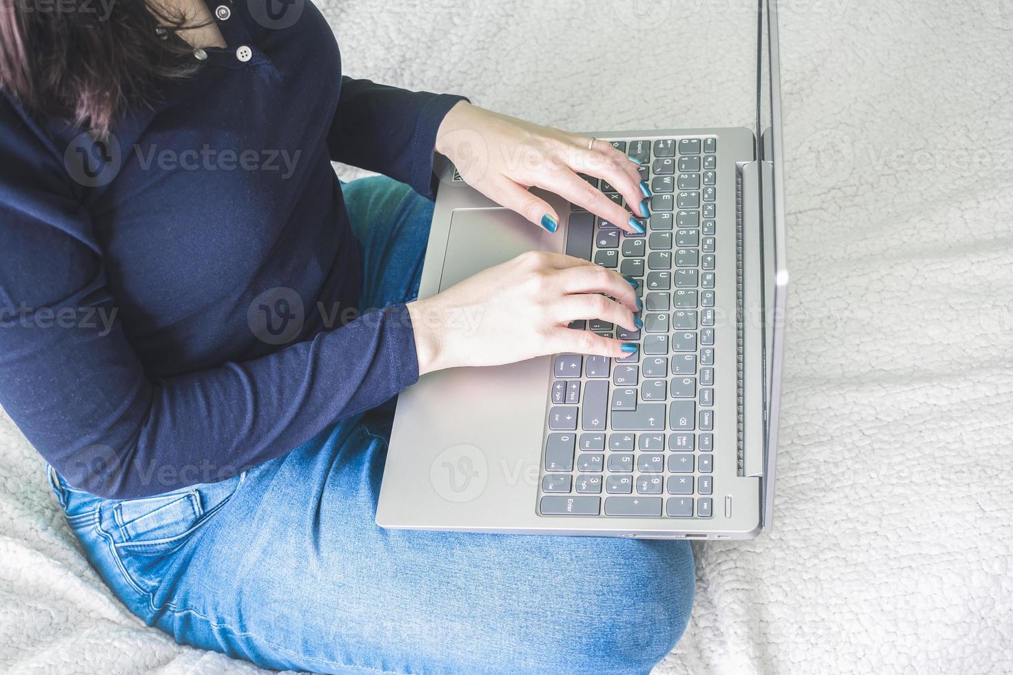 jonge vrouw zittend op bed met laptop op schoot. foto