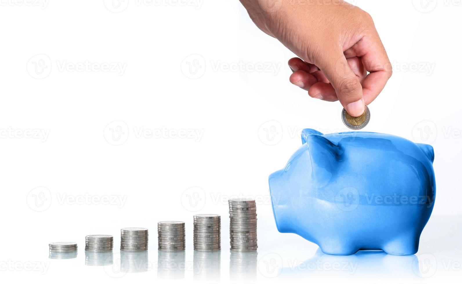 het concept om geld te besparen, hand die een muntstuk in spaarvarken op witte achtergrond zet foto