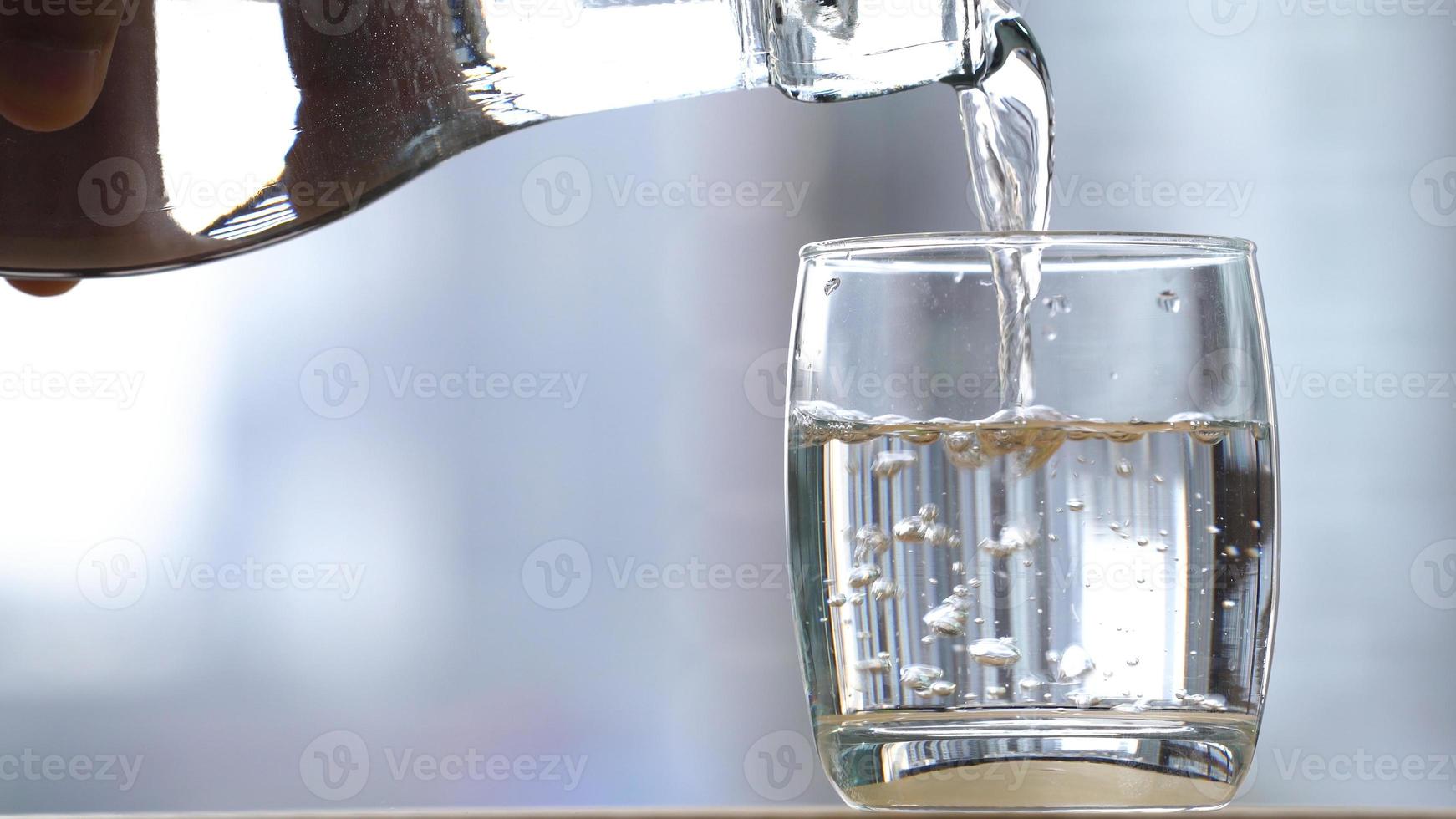 drink water dat in een glas op tafel stroomt foto