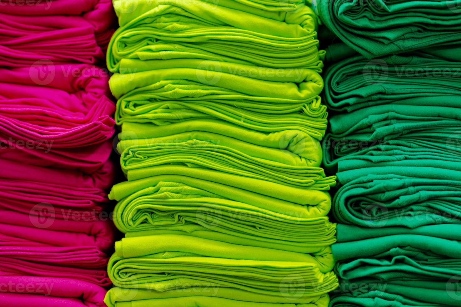 close-up van kleurrijke t-shirts gestapeld op planken foto