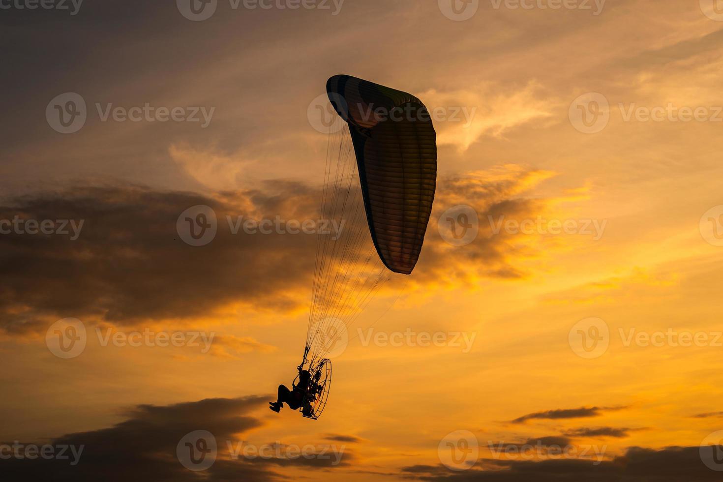 het silhouet van de paramotor bij zonsondergang foto