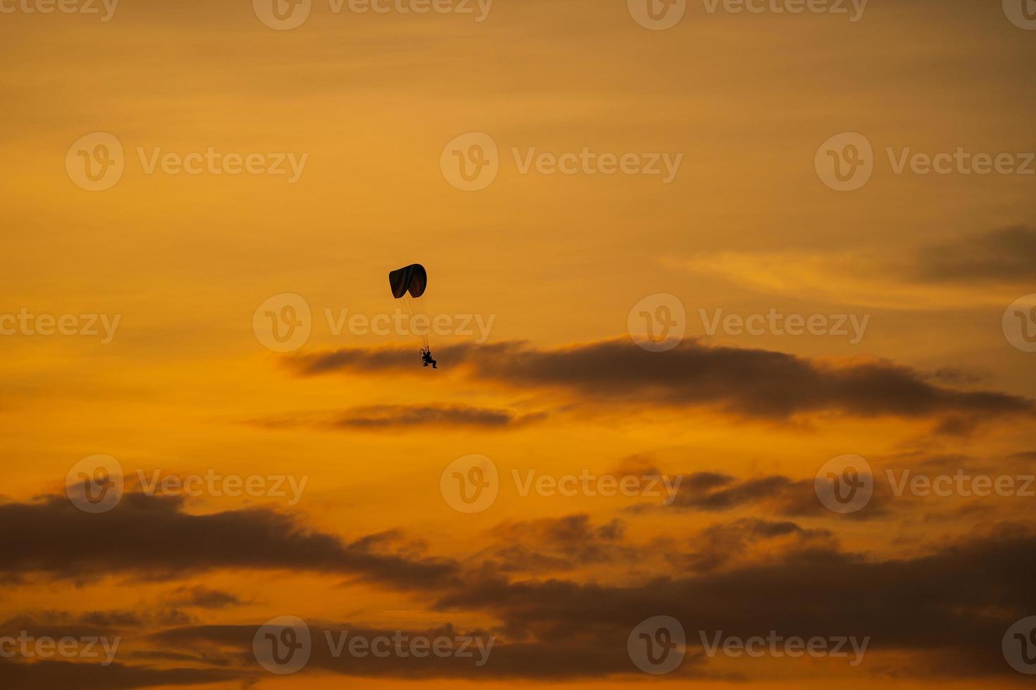 het silhouet van de paramotor bij zonsondergang foto