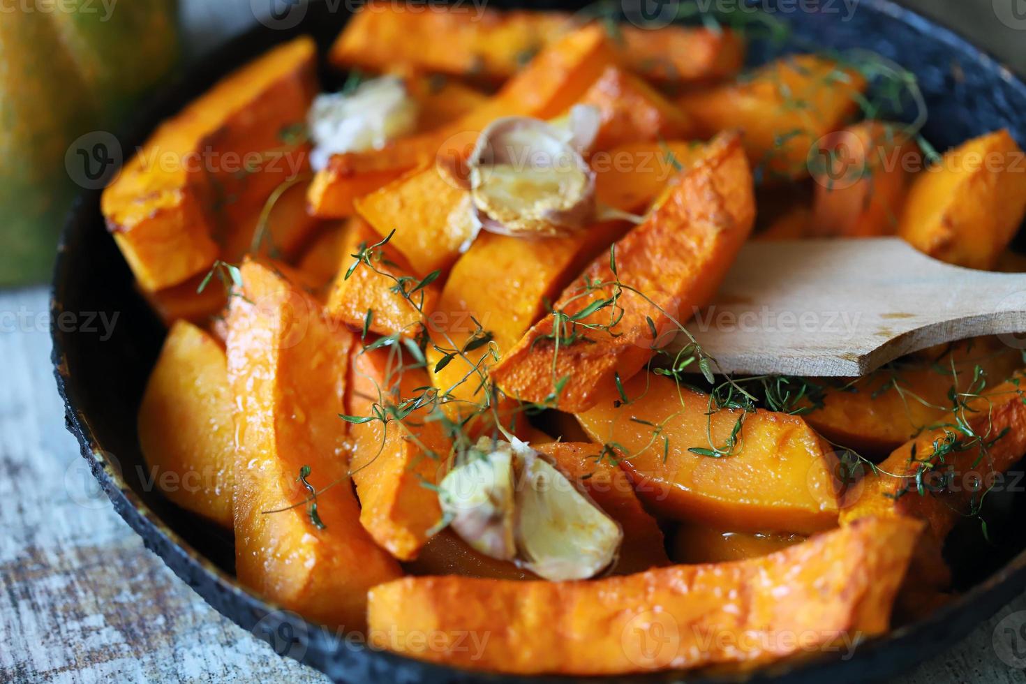 gebakken pompoenschijfjes in een pan met kruiden en knoflook foto