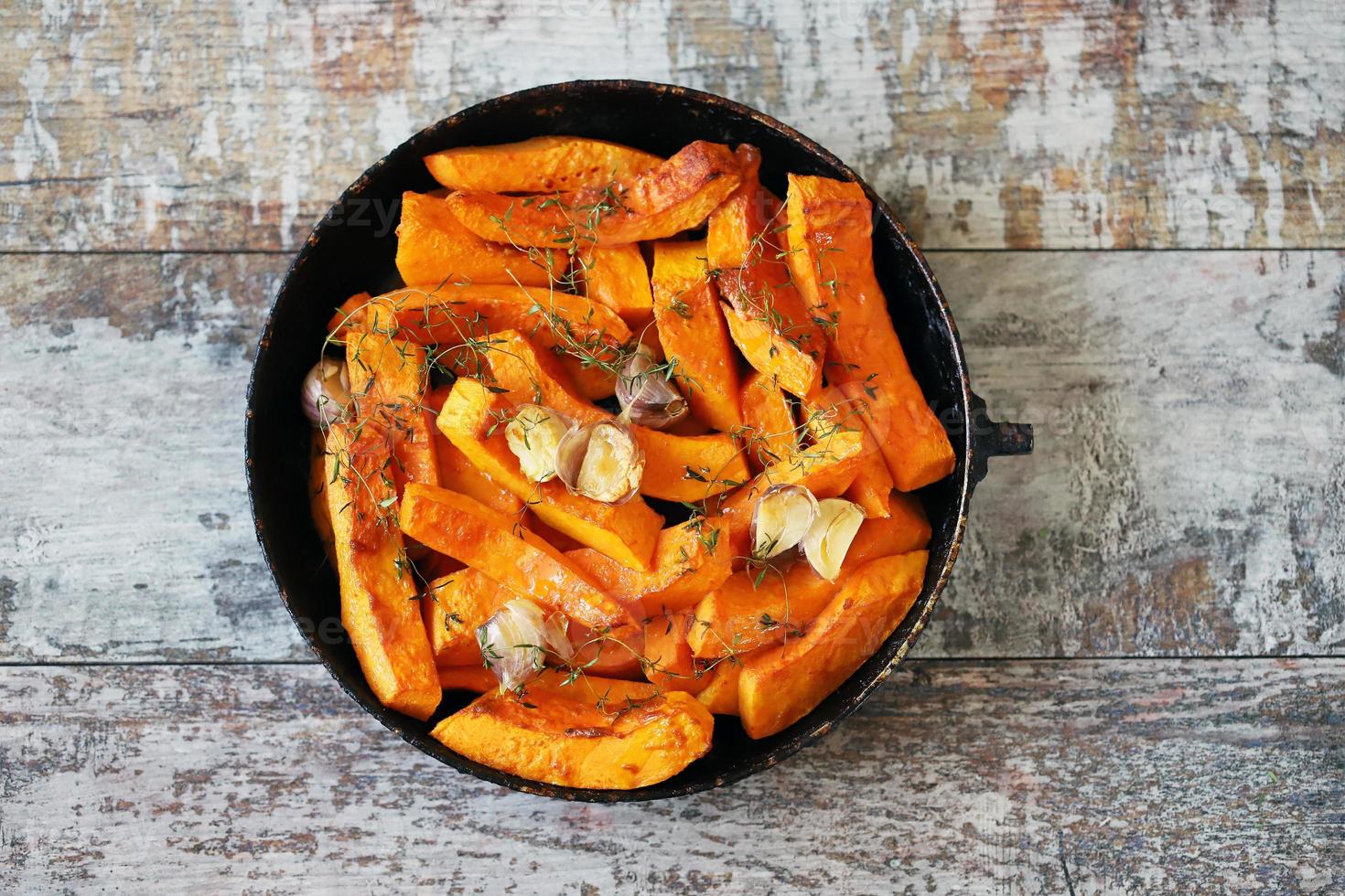 gebakken pompoenschijfjes in een pan met kruiden en knoflook foto