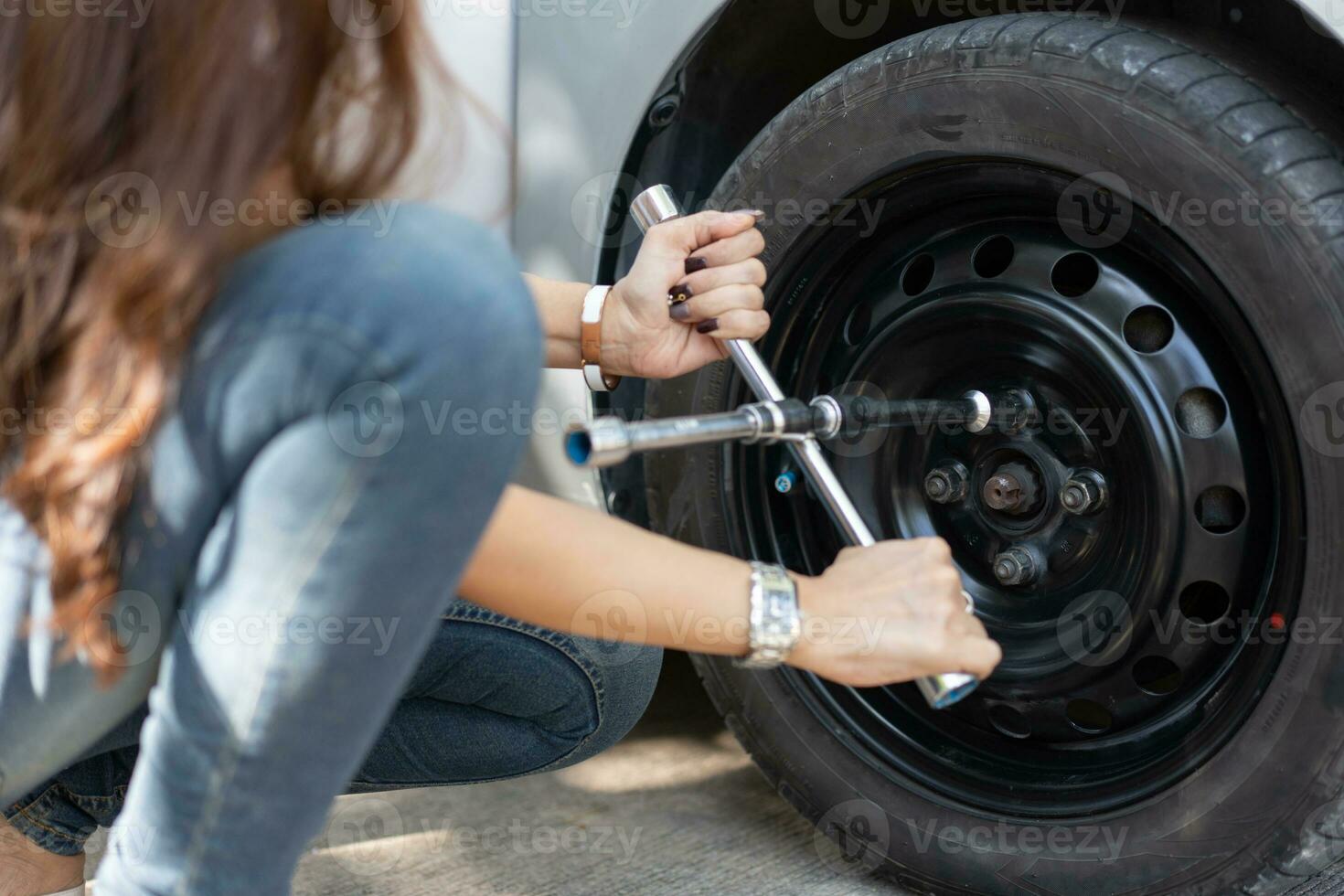 slim en aantrekkelijk Aziatisch vrouw aansluitingen omhoog haar auto en toepassingen een moersleutel naar verandering de wiel Aan een gebroken auto, toepassingen gereedschap of apparatuur, probeert naar oplossen problemen door zelf, auto repareren en verzekering concept foto