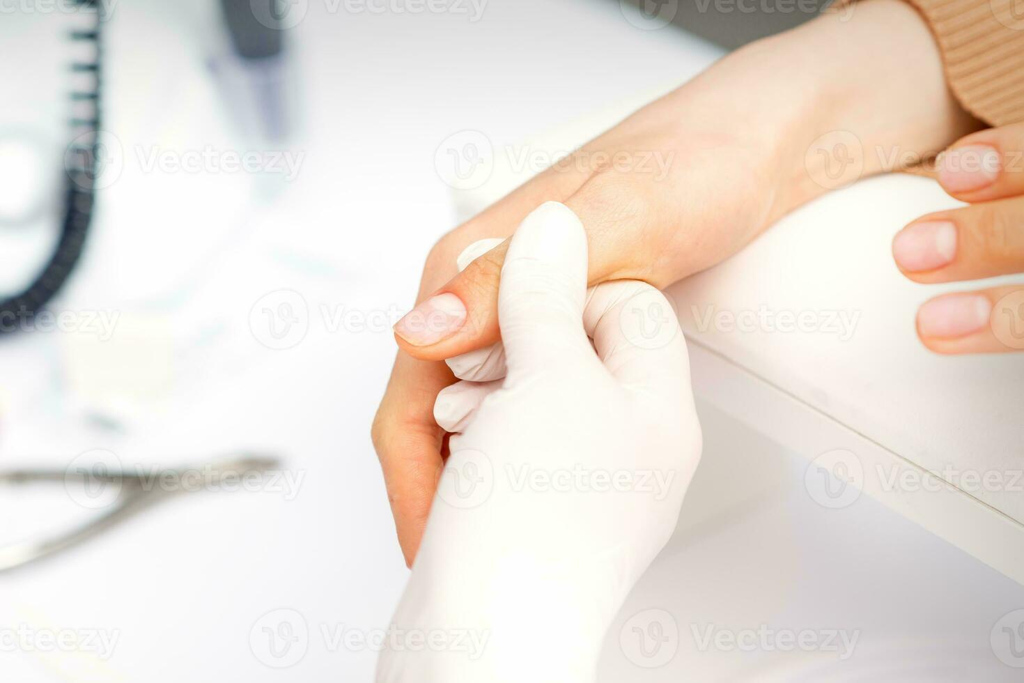 de manicure houdt de vrouw duim gedurende een manicure procedure in de nagel salon. foto