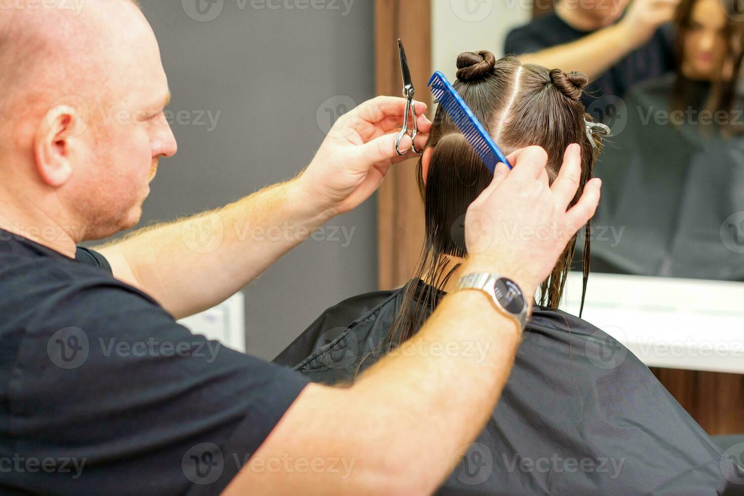 mannetje stilist snijdend de haar- van vrouw cliënt in professioneel schoonheid salon. foto