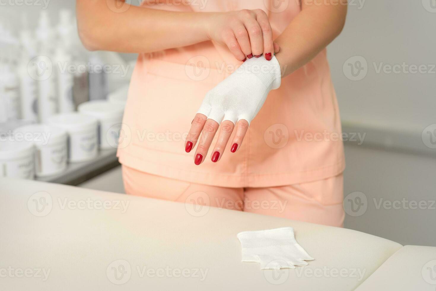 schoonheidsspecialist in werkkleding vervelend wit bamboe vingerloos handschoenen Aan haar handen. foto