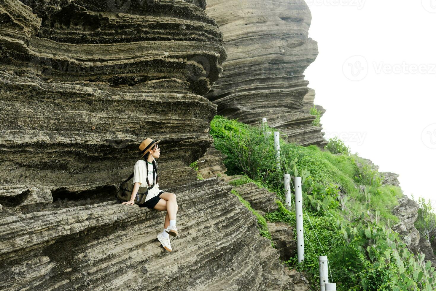beeld van een meisje zittend Aan een majestueus klif foto