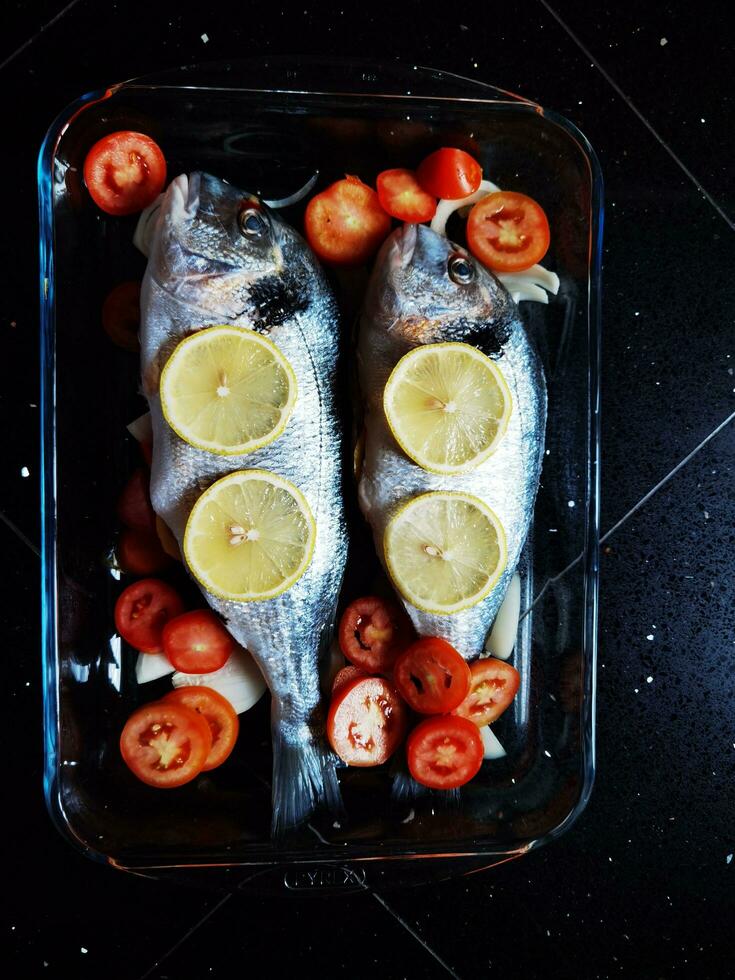 een schotel van zee bas met kers tomaten gekookt in de oven, in een heerlijk Italiaans keuken van Ligurië foto