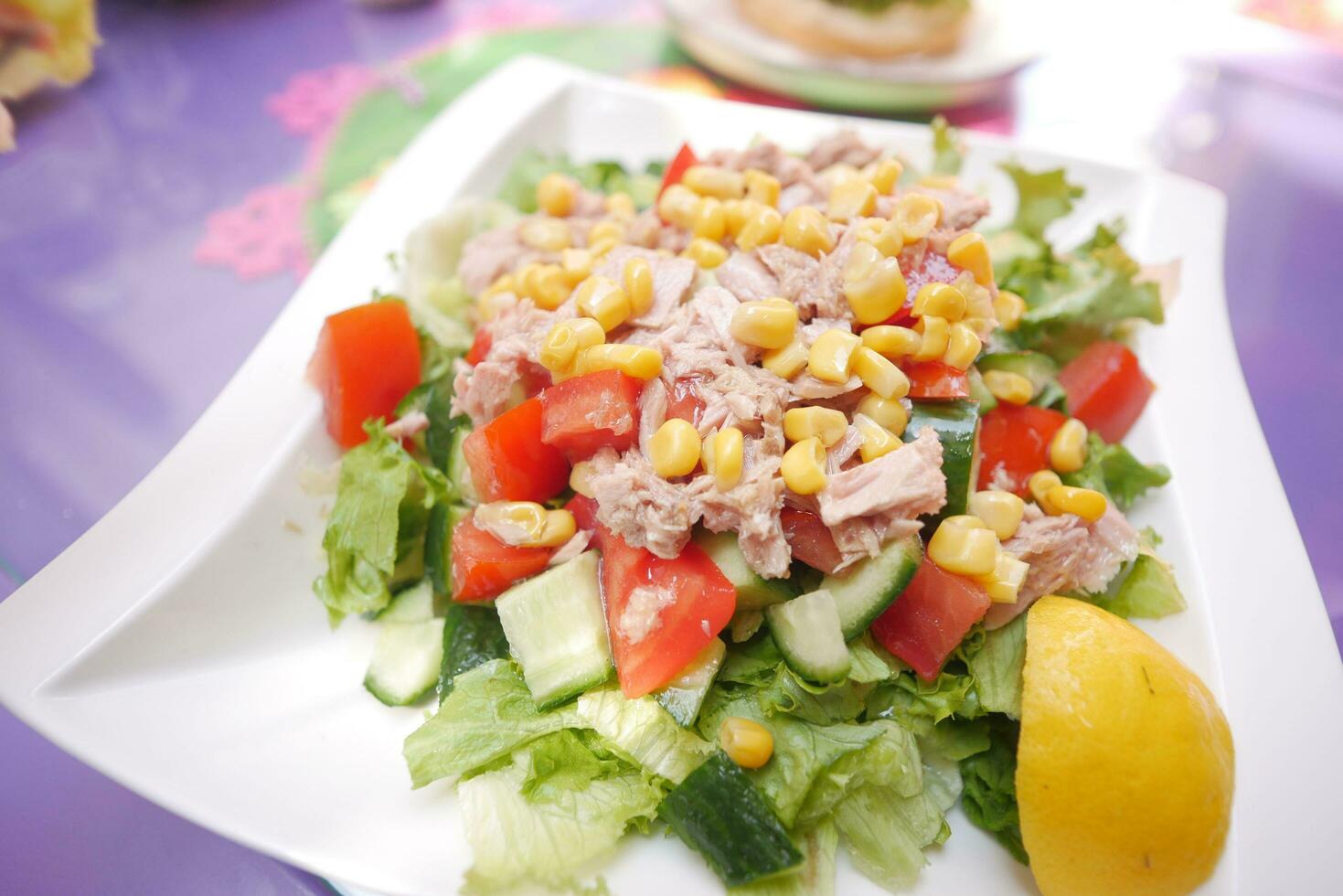 lepel plukken tonijn salade van een kom Aan tafel foto