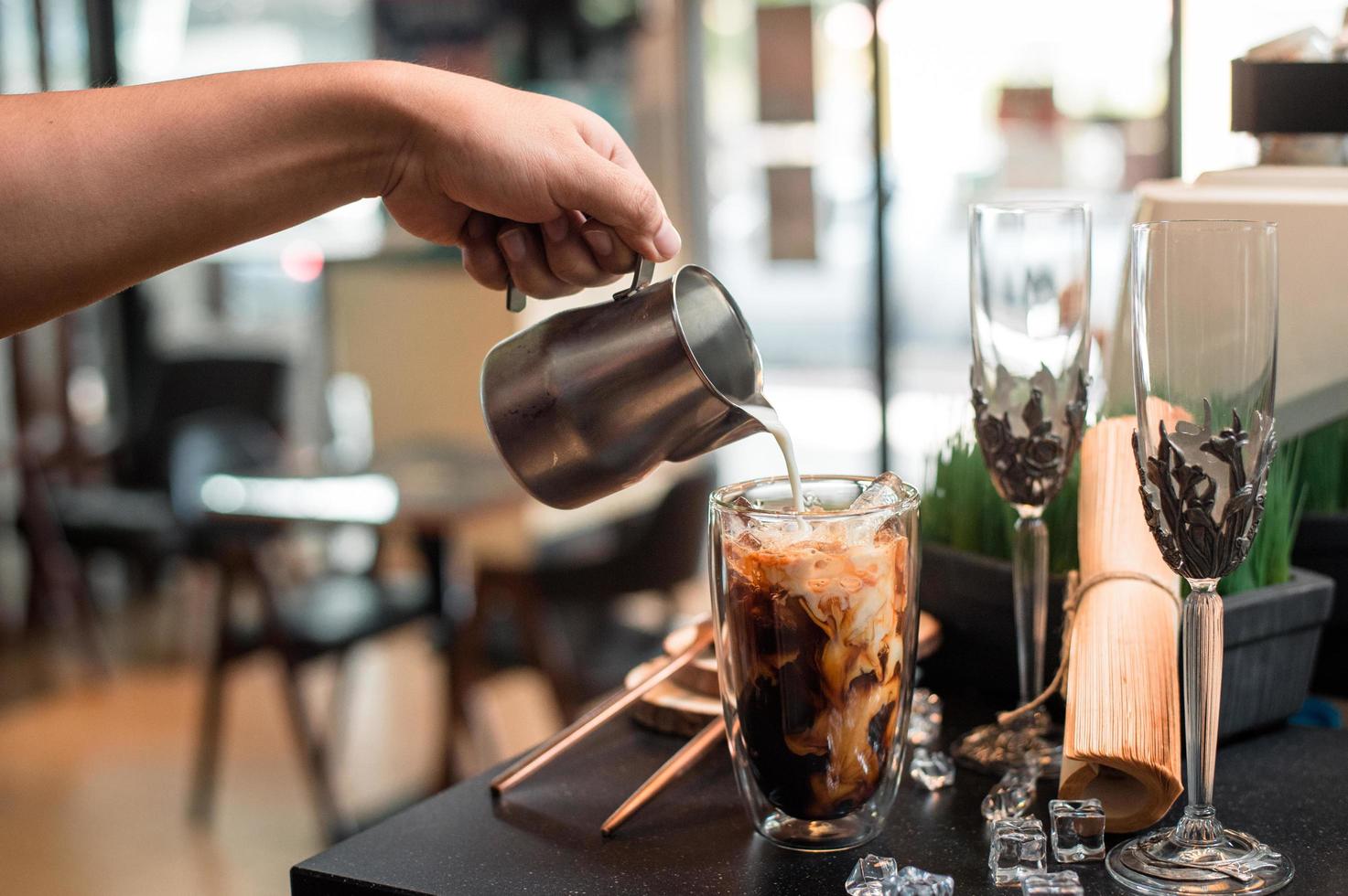 barista melk gieten in een glas ijskoffie foto