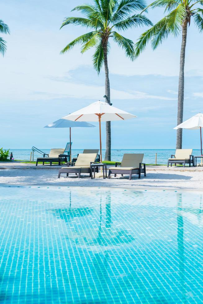 prachtig tropisch strand en zee met parasol en stoel rond zwembad in hotelresort foto