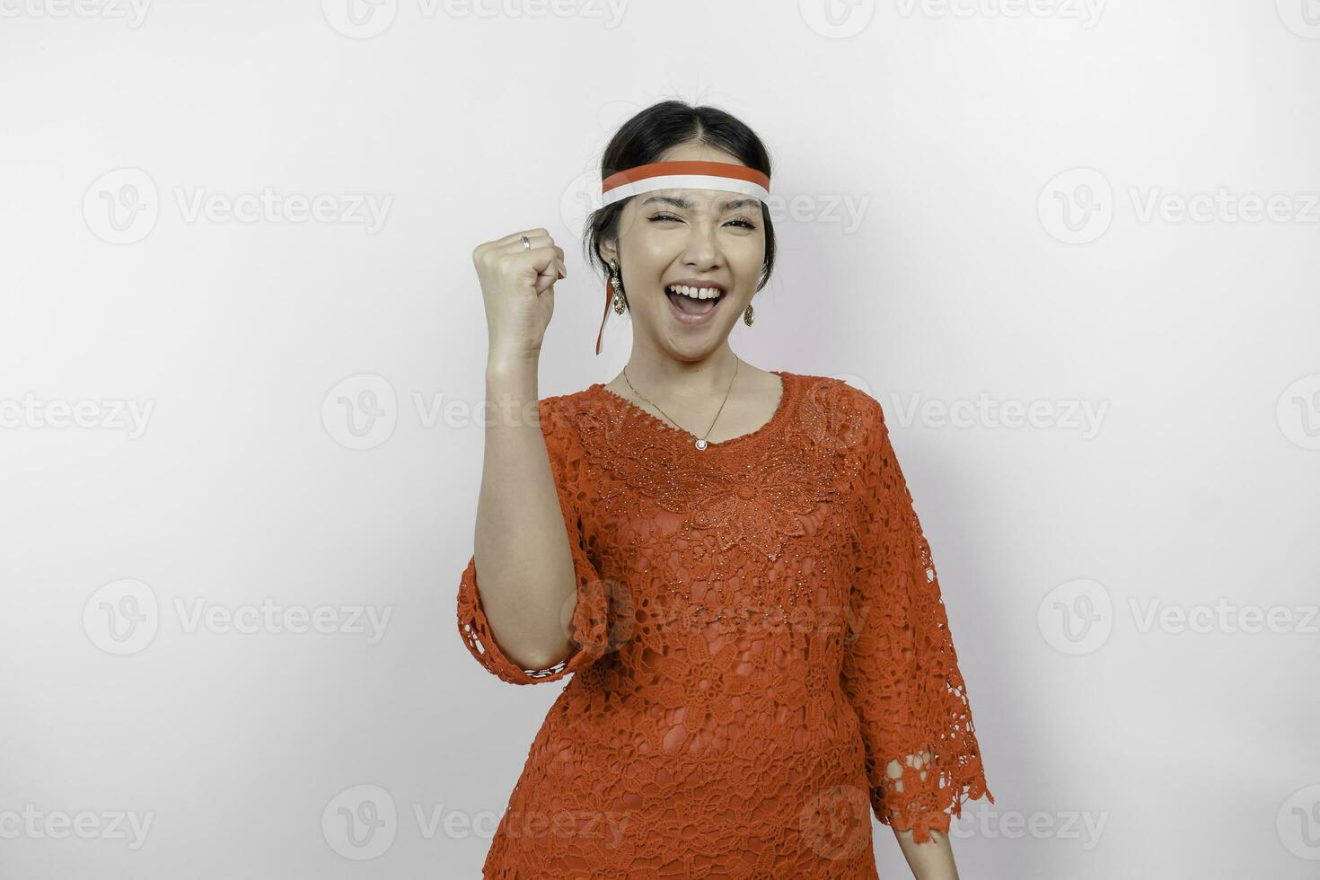 een jong Aziatisch vrouw met een gelukkig geslaagd uitdrukking vervelend rood kebaya en hoofdband geïsoleerd door wit achtergrond. Indonesië's onafhankelijkheid dag concept. foto