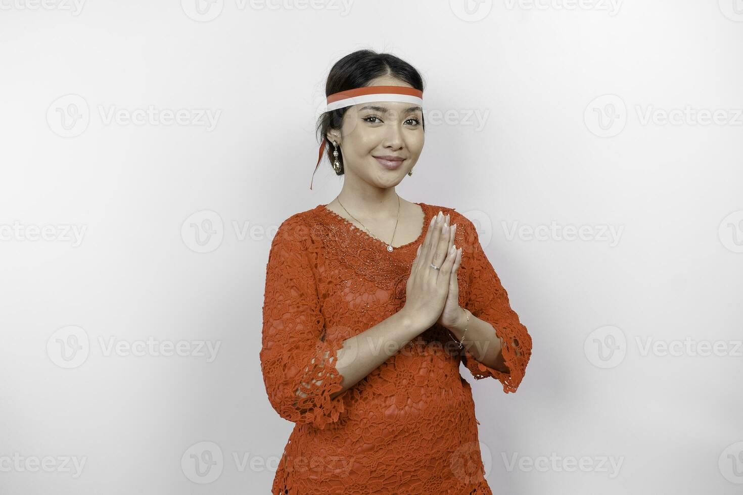 een vriendelijk Indonesisch vrouw is vervelend rood kebaya gebaren traditioneel groet en Indonesië's vlag hoofdband naar vieren Indonesië onafhankelijkheid dag. geïsoleerd door wit achtergrond. foto