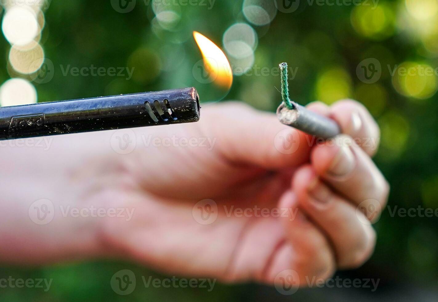 persoon brand omhoog voetzoeker. persoon Holding aansteker en voetzoeker. het schieten voetzoekers en vuurwerk. foto