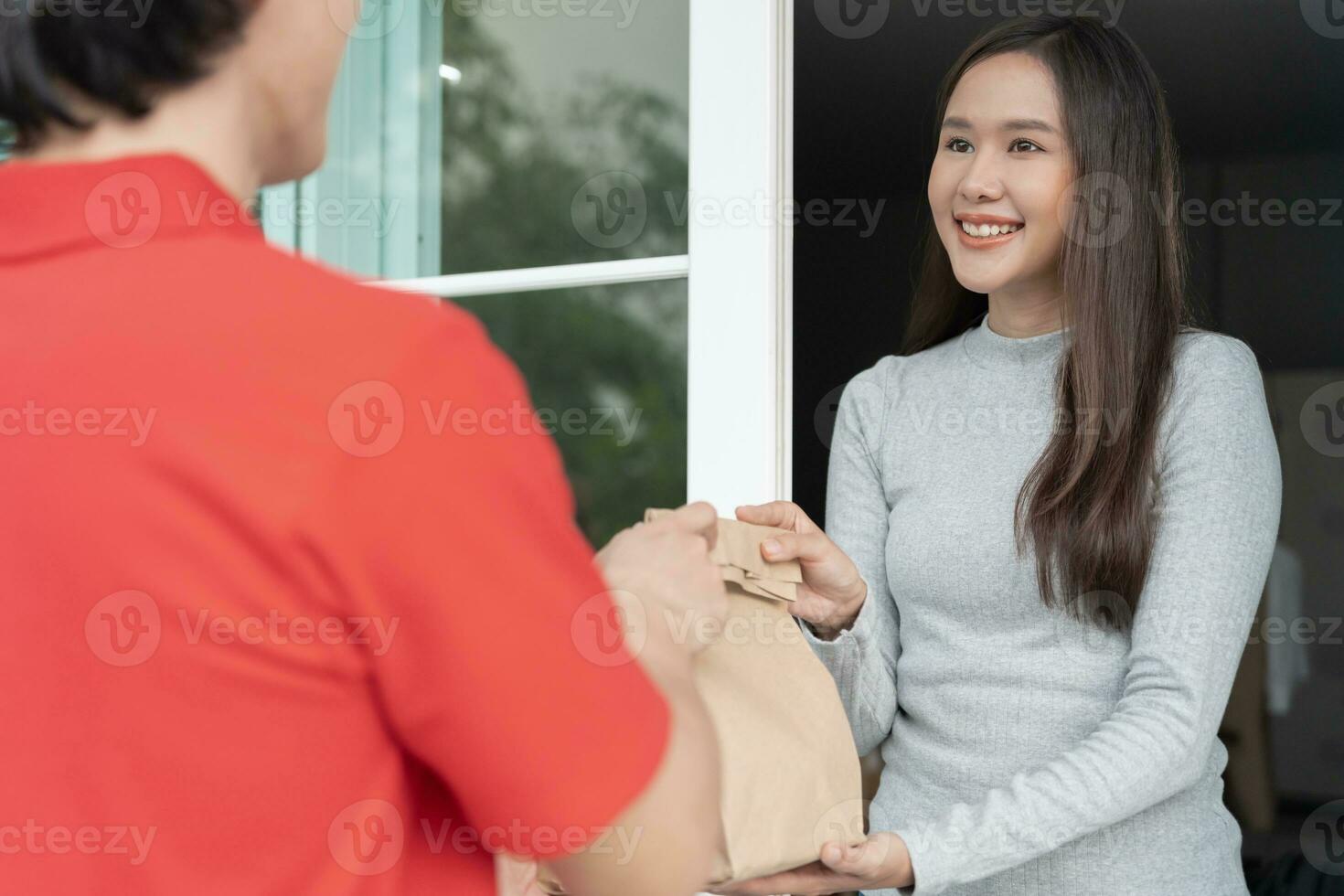 gelukkig glimlachen Aziatisch vrouw ontvangt papier zak pakket van voedsel van koerier voorkant huis. levering Mens sturen leveren uitdrukken. online winkelen, papier container, afhalen, postbode, levering onderhoud, pakketjes foto